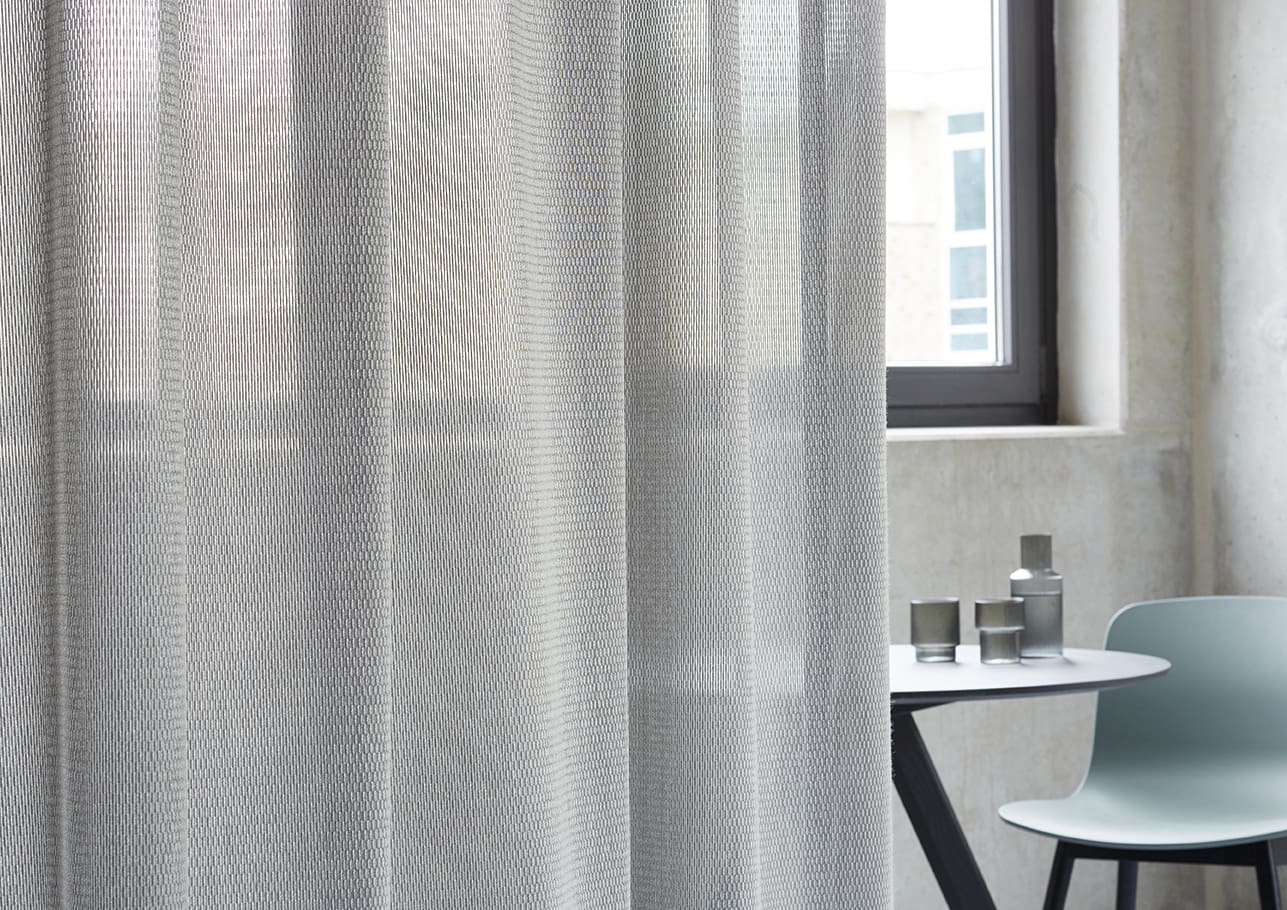 A white curtain in front of a window.