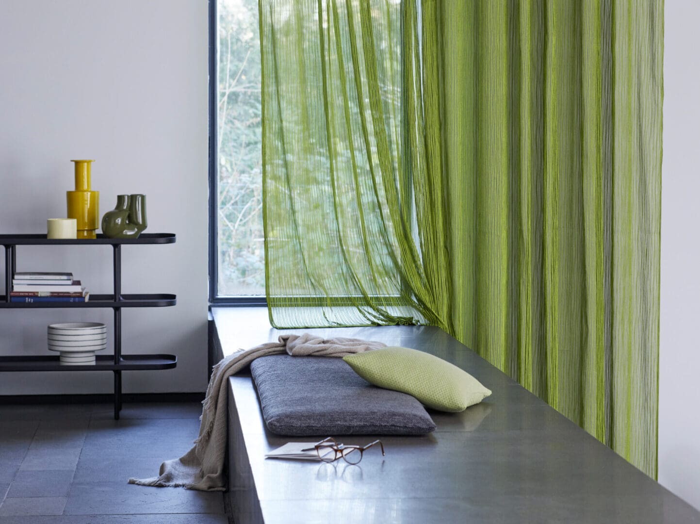 A room with green curtains and pillows on the bench.