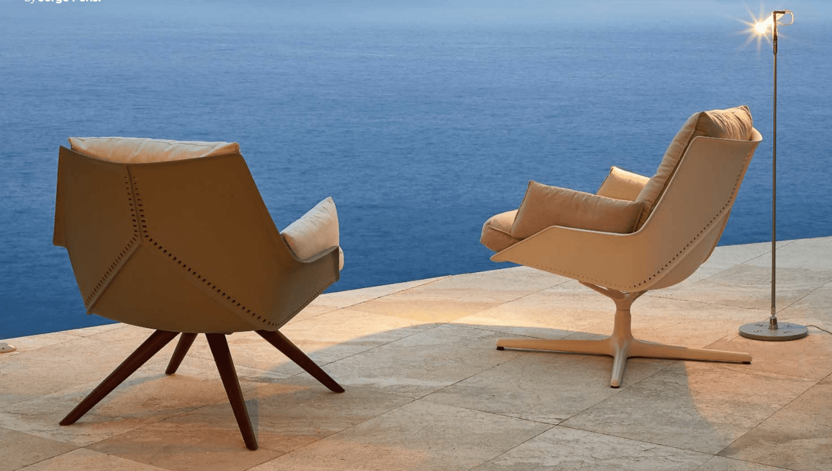 Two chairs on a patio near the ocean.